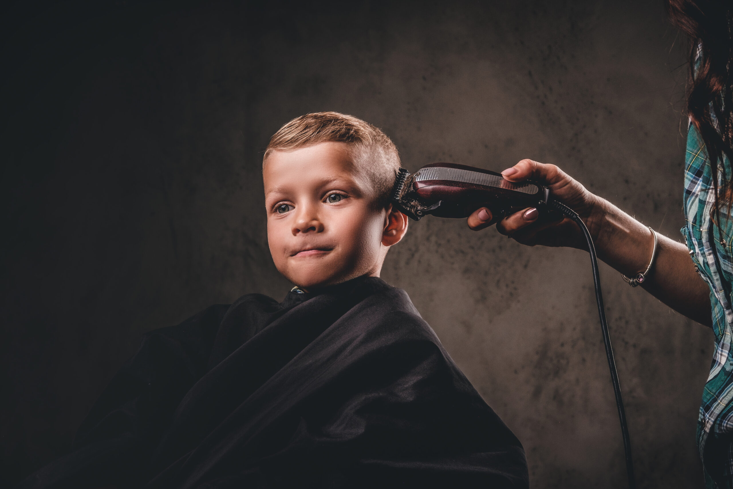 Cute preschool boy getting haircut