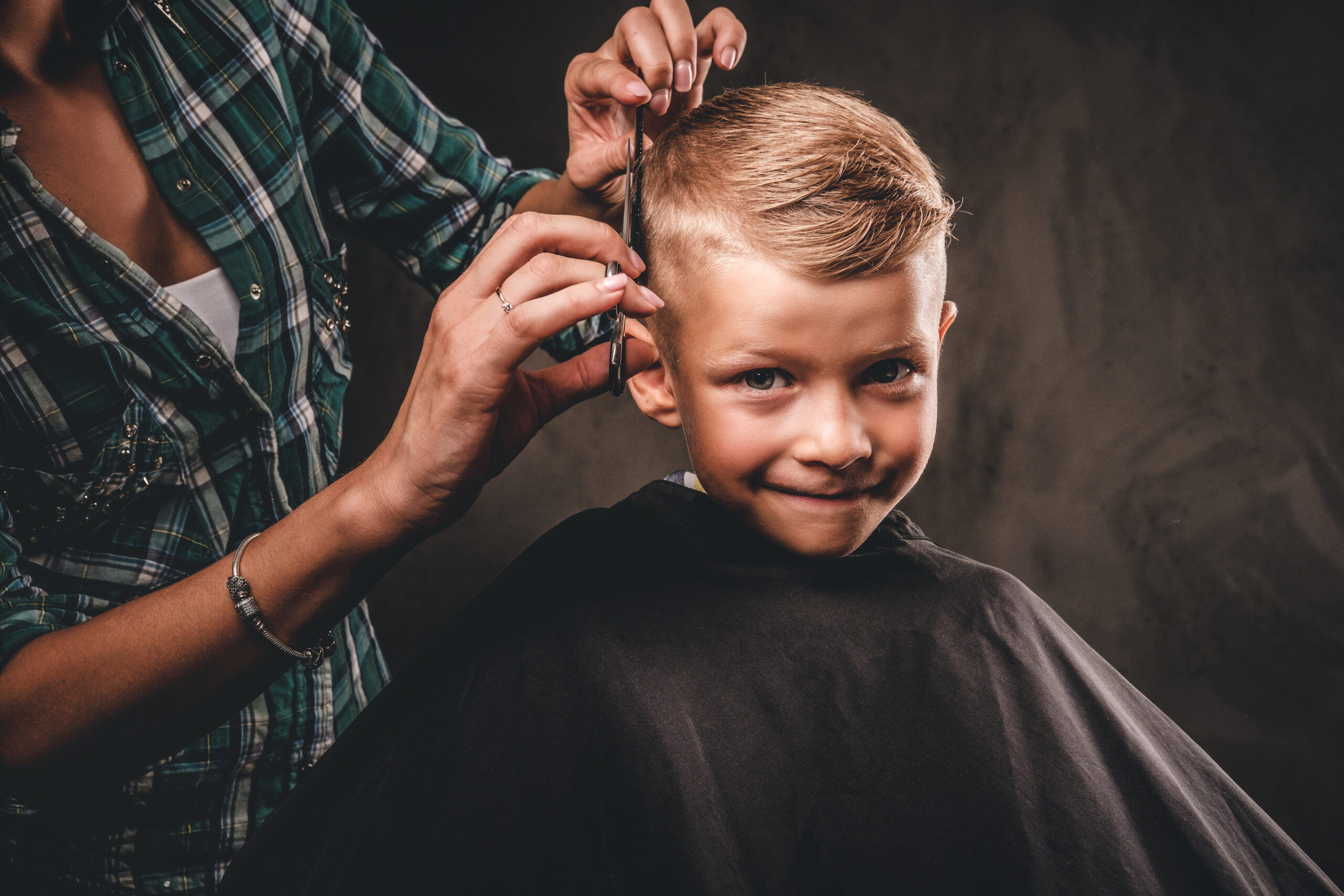 Cute preschool boy getting haircut